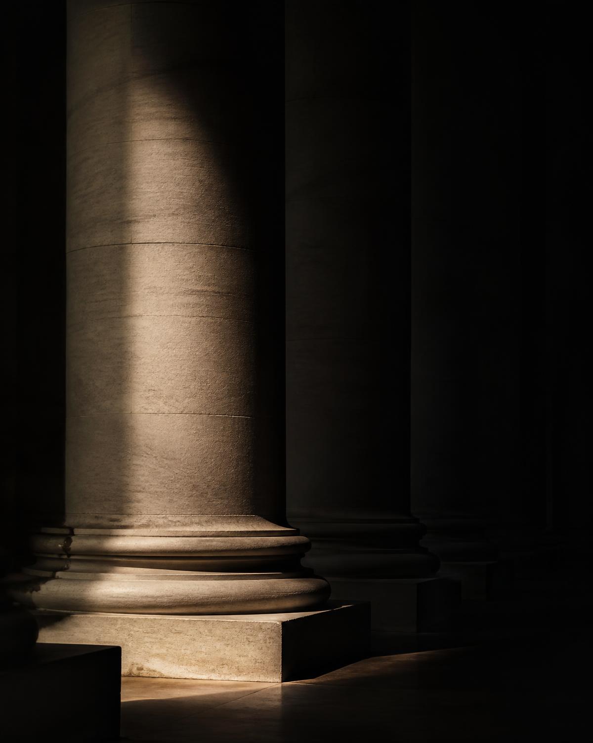 Monumental stone columns lit by a single shaft of light